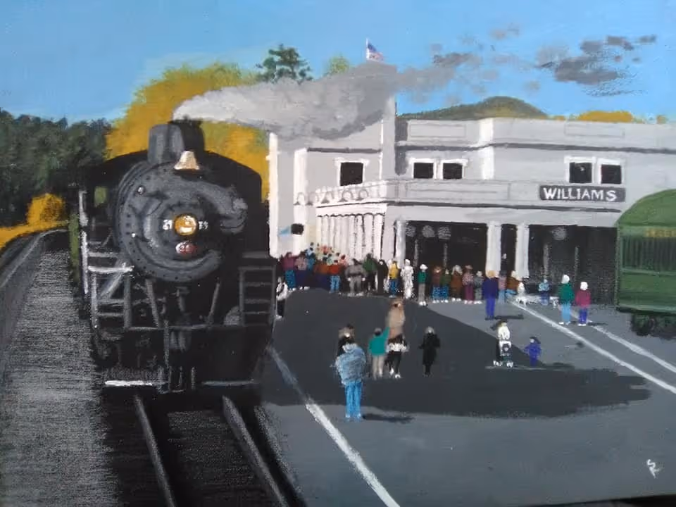 Acrylic painting of a black steam locomotive pulling into the Williams, Arizona depot with a crowd on the platform, autumn trees, and a green heritage rail car.
